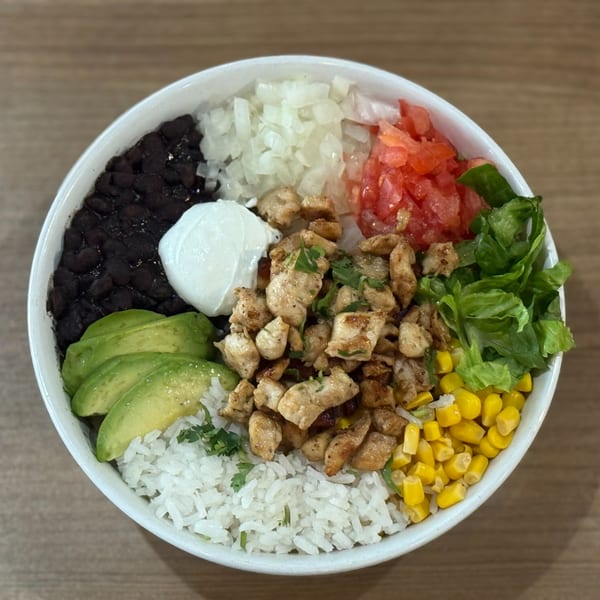 Nazca Express chicken bowl with rice, black beans, avocado, corn, lettuce, tomatoes, onions, and sour cream.